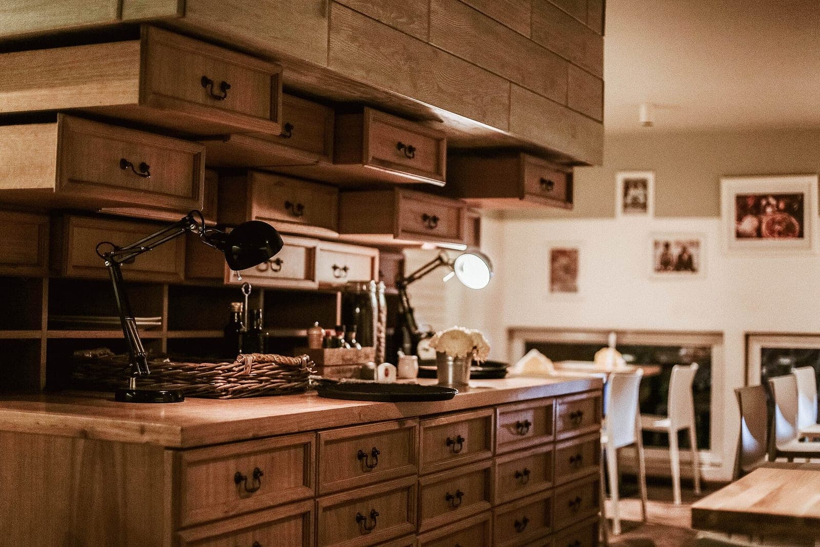 Rows of wooden drawers and two desk lamps on a wooden counter in a warmly lit room