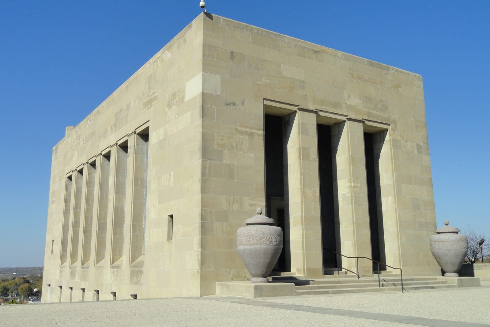 A pale limestone hall with tall columns and stone urns at the Liberty Memorial in Kansas City, Missouri, under a clear blue sky
