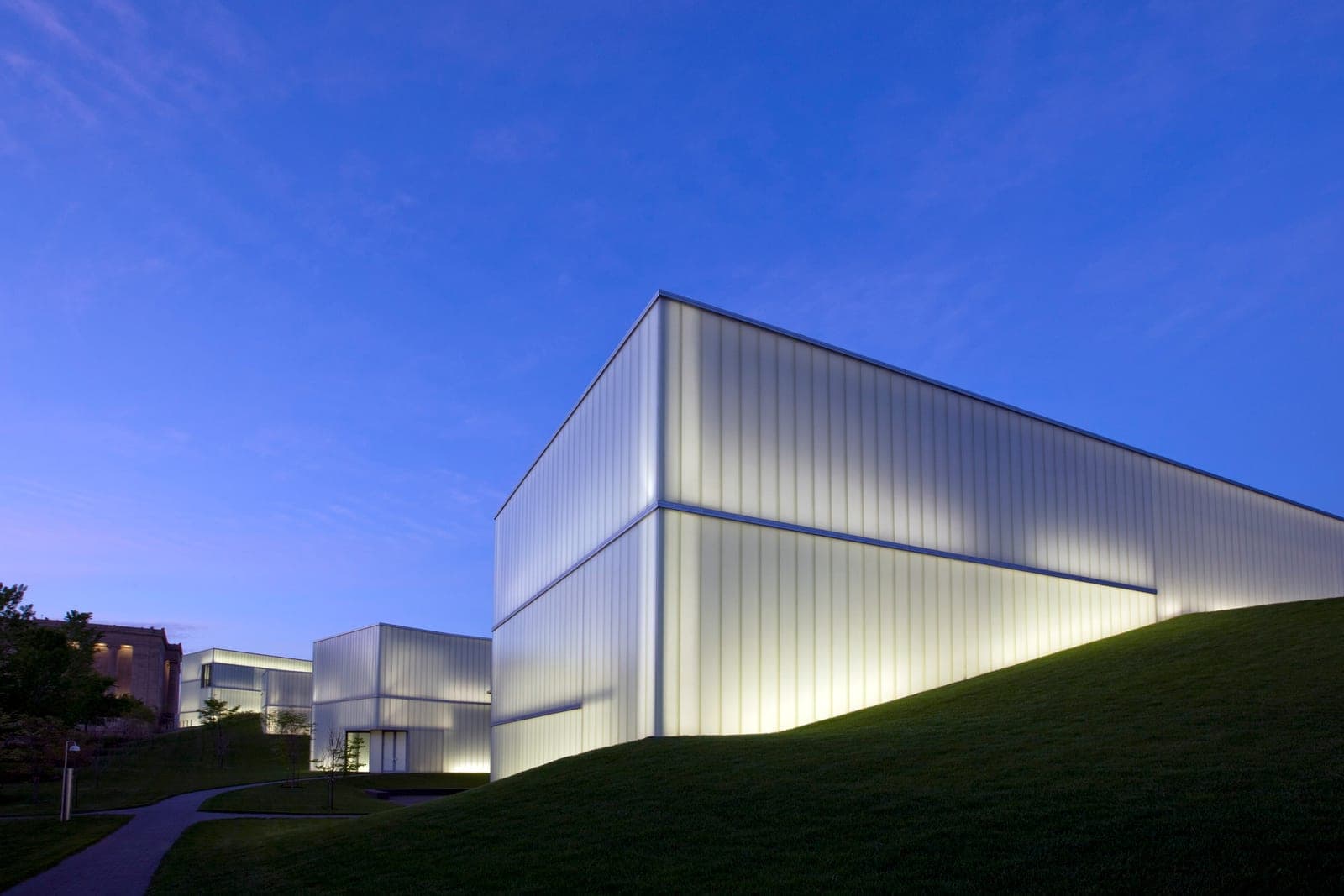 The glass Bloch Building of the Nelson-Atkins Museum of Art glowing on its lawn at dusk in Kansas City, Missouri
