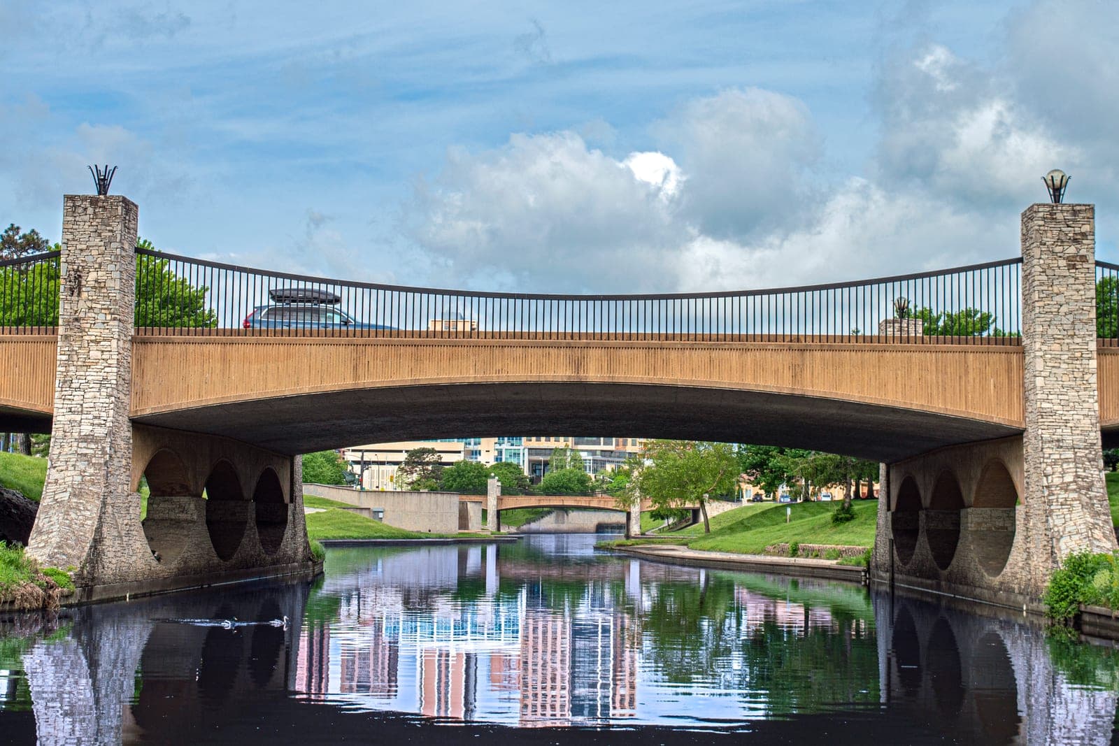 A stone-pillared bridge crosses the creek on the Country Club Plaza in Kansas City, Missouri, with buildings mirrored in the water