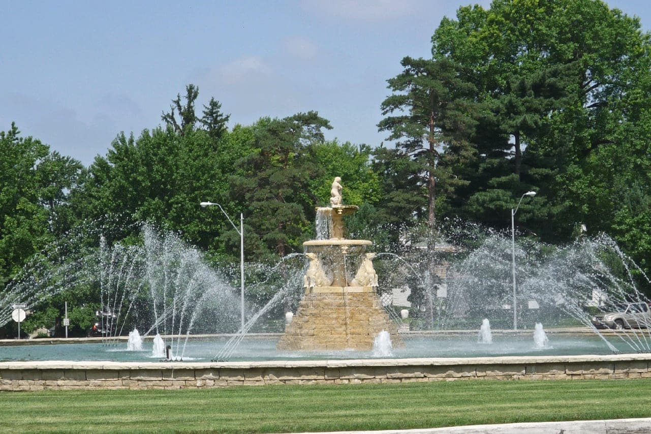 The Meyer Circle Sea Horse Fountain spraying in a grassy circle among summer trees in Kansas City, Missouri