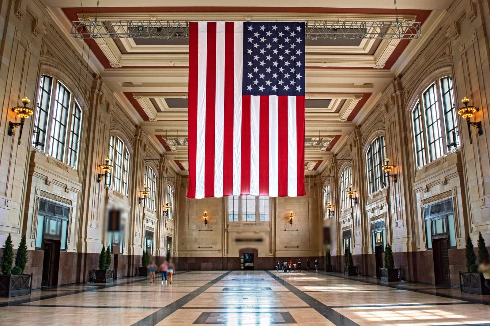 The great hall inside Union Station in Kansas City, Missouri, with tall arched windows, a coffered ceiling and a giant American flag