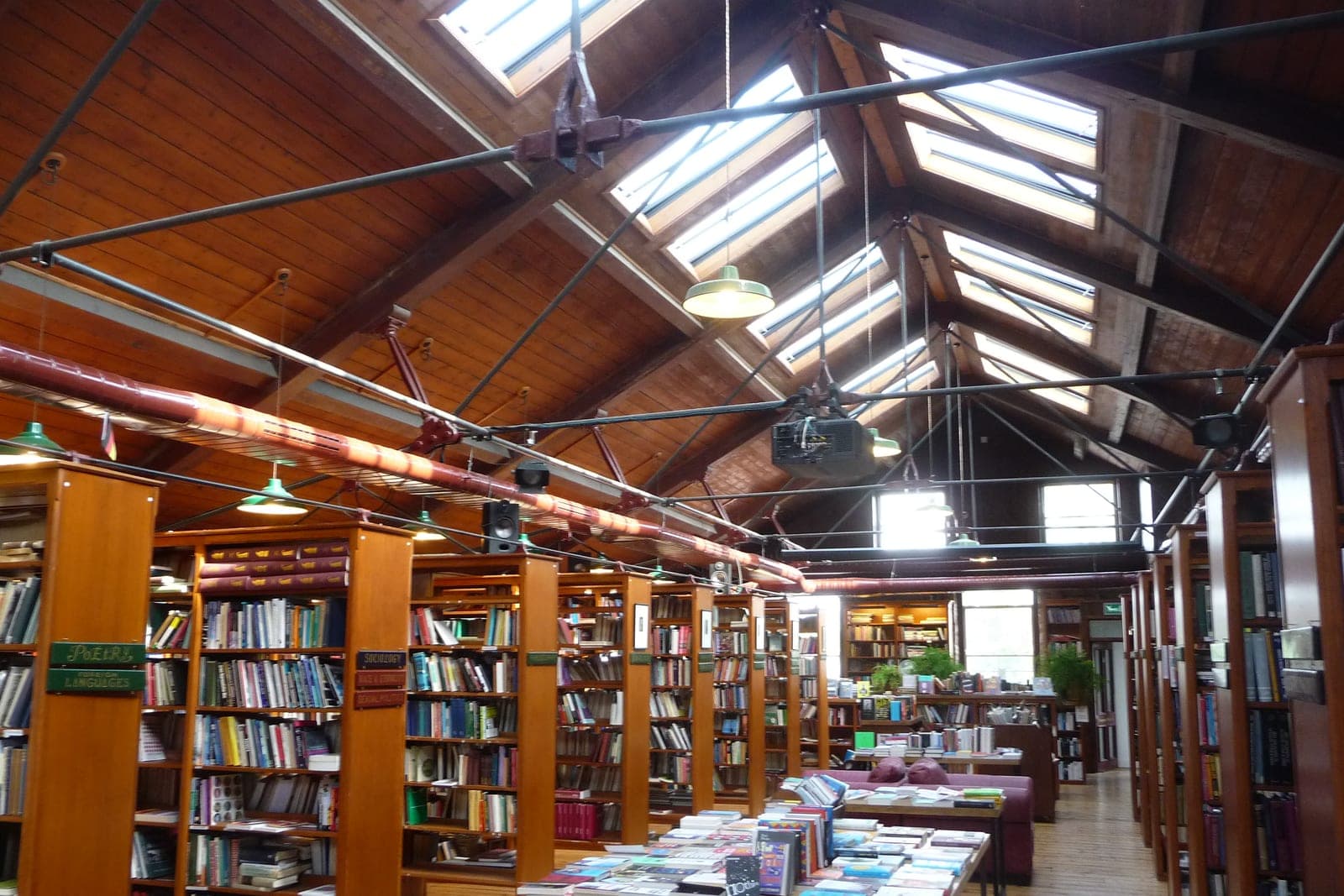 Rows of wooden bookshelves under a skylit ceiling in a large bookshop