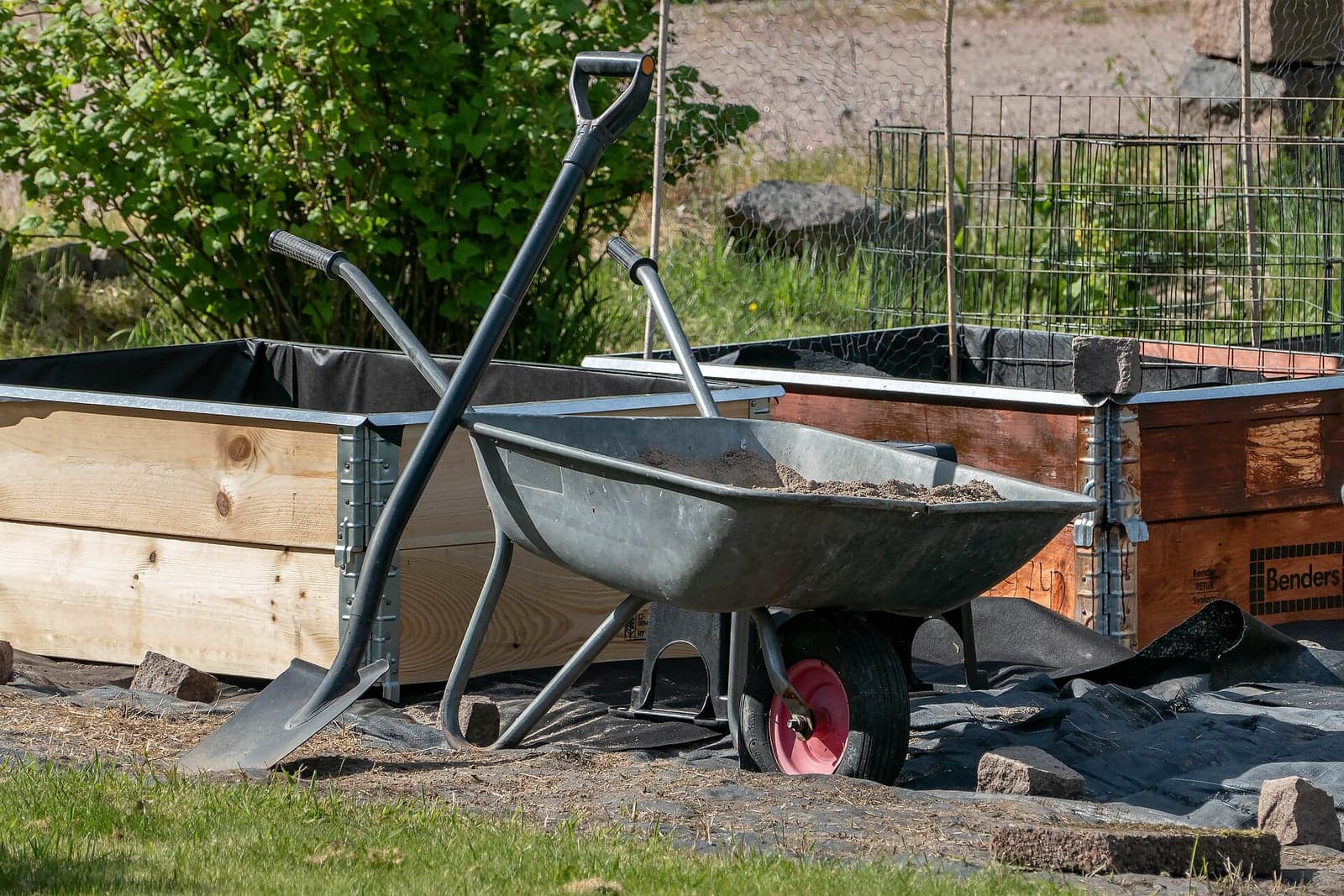 A spade and a wheelbarrow beside raised garden beds