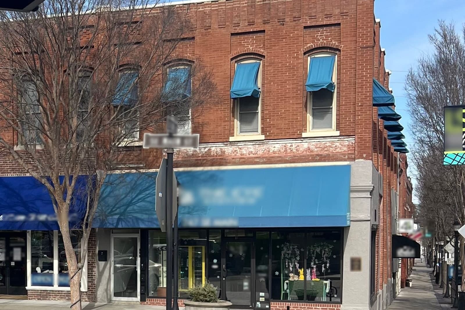 A two-story brick corner building with blue awnings on Main Street in downtown Lee's Summit, Missouri