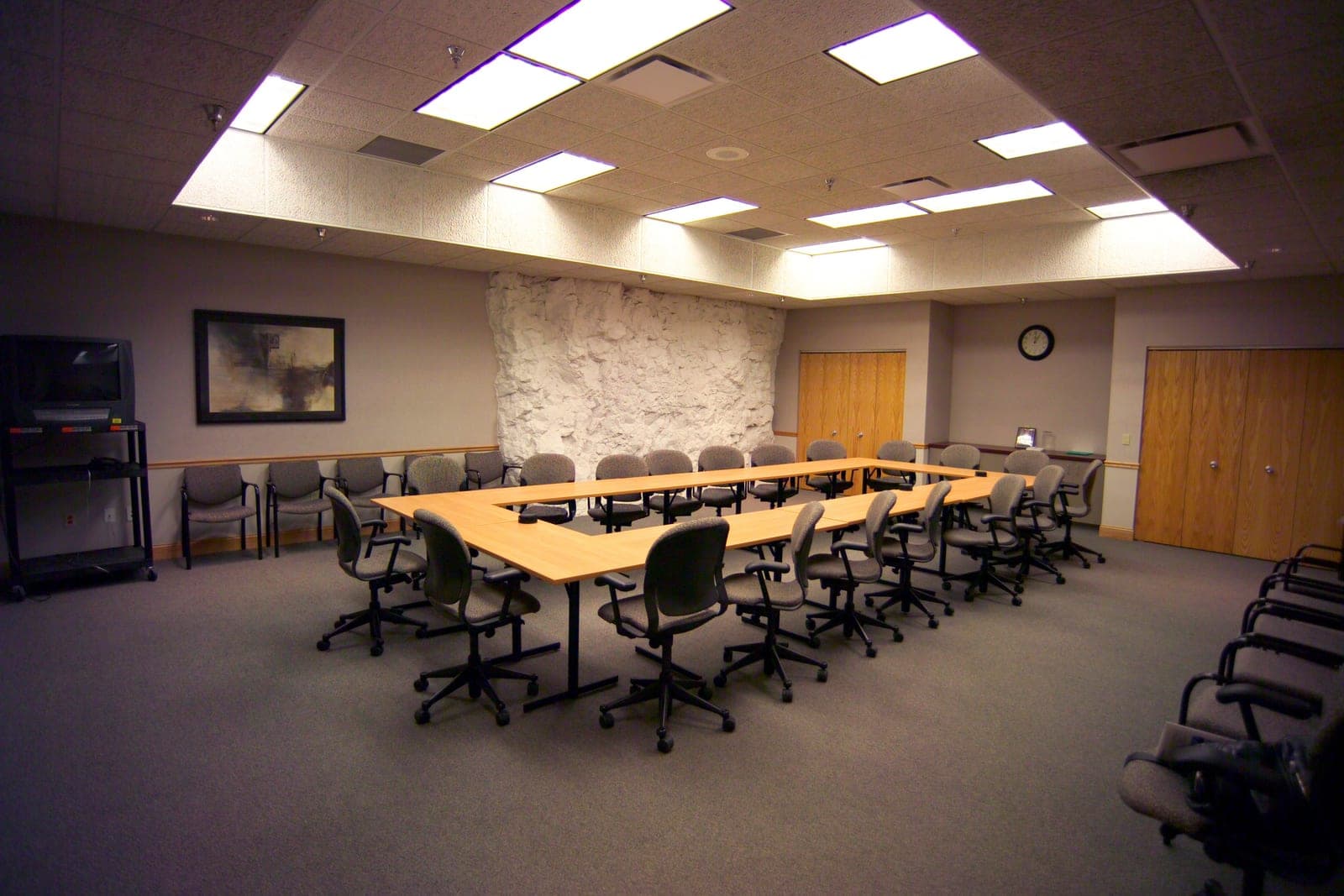 An empty conference room with tables arranged in a square and rows of office chairs