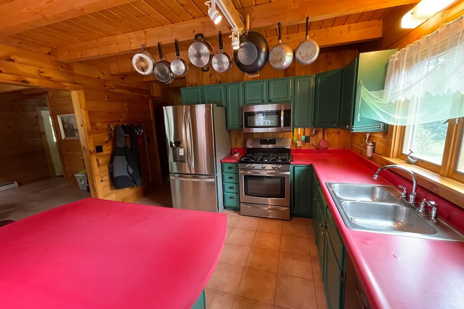 A wood-paneled kitchen with a stainless steel refrigerator, gas range and microwave