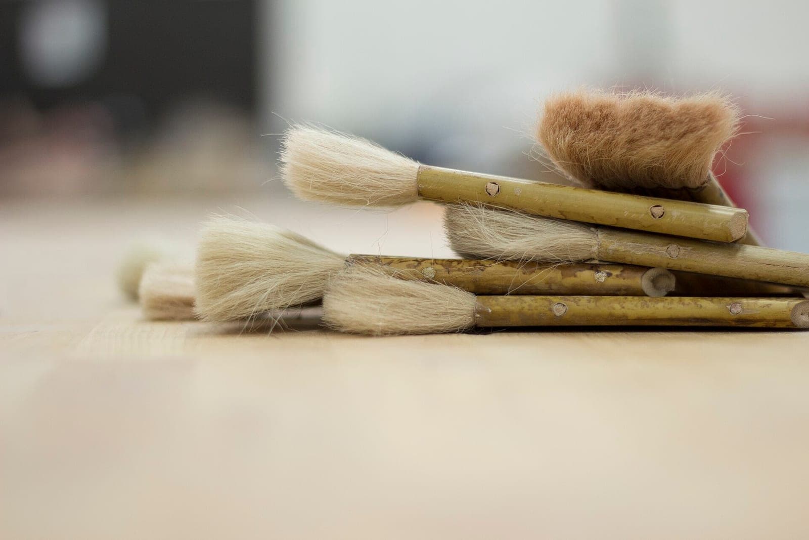 Several paint brushes with natural bristles lying on a wooden table