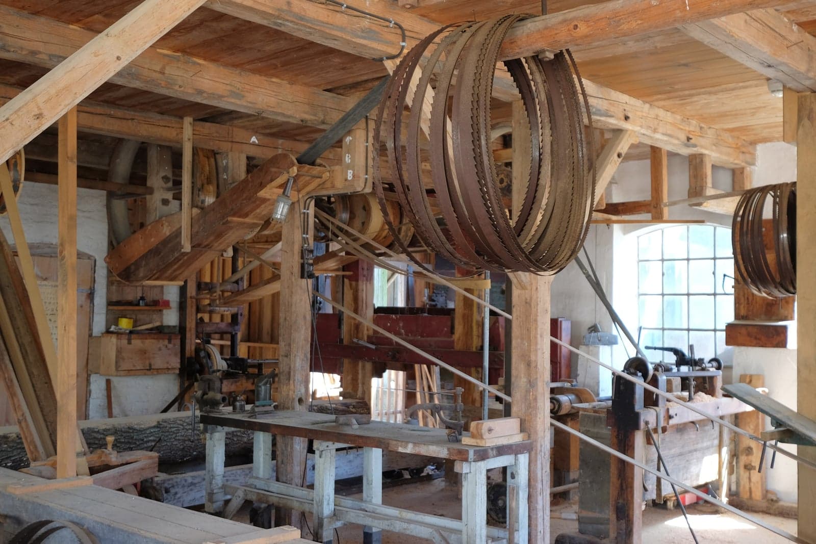 A carpenter at work in a bright wooden workshop full of tools and timber