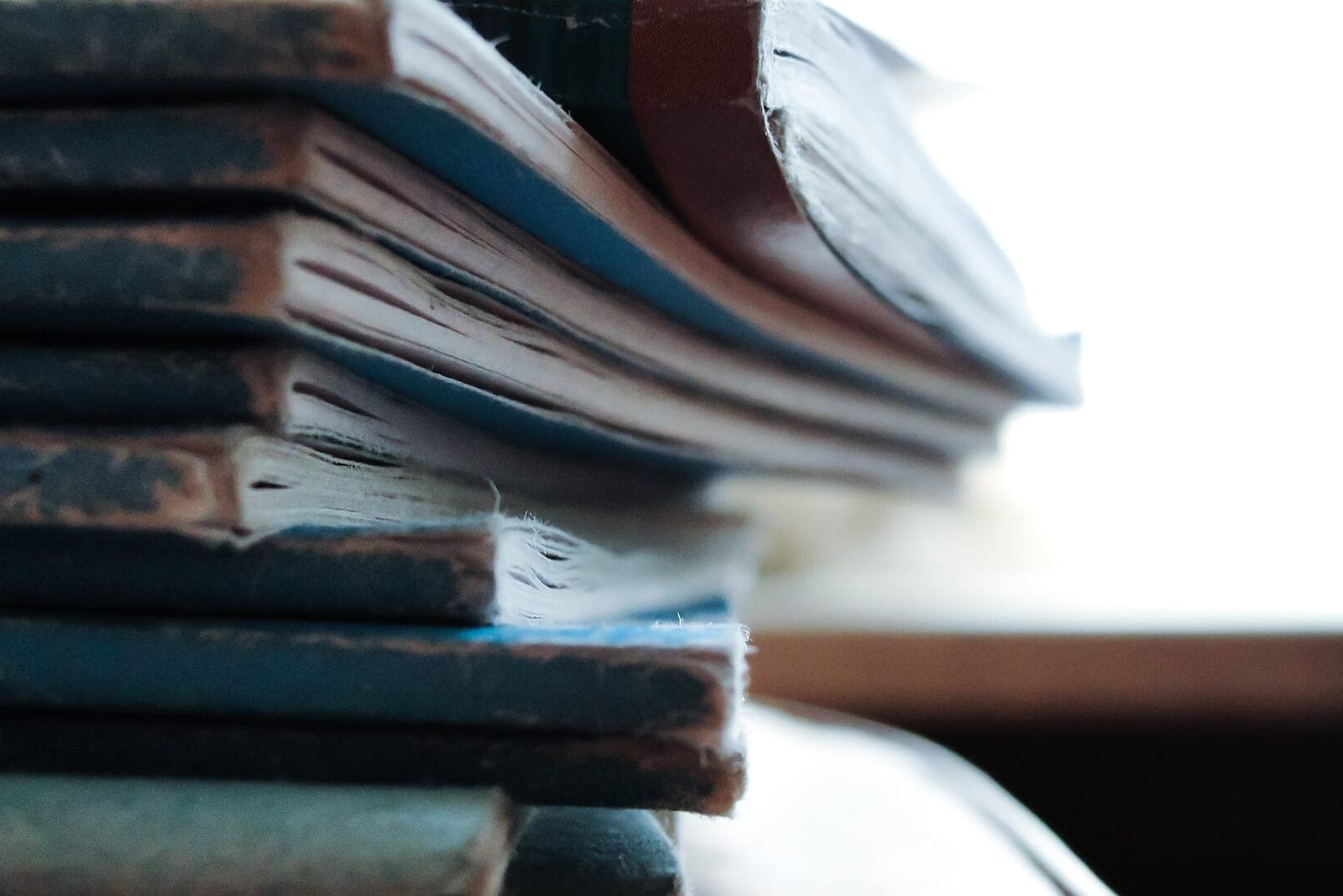 A close view of a stack of worn paper notebooks and folders on a desk