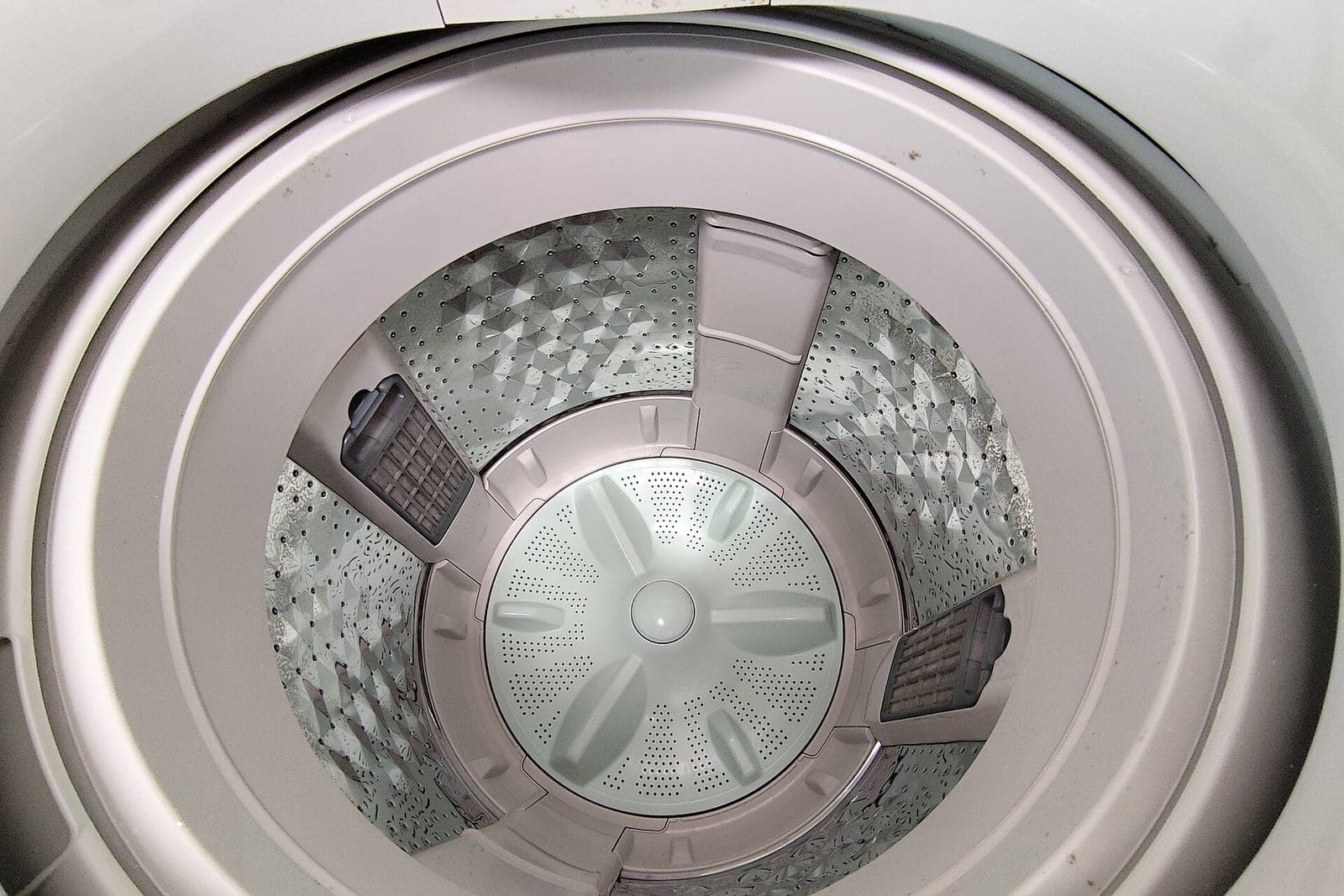 Inside a top-load washing machine, showing the drum and the agitator plate