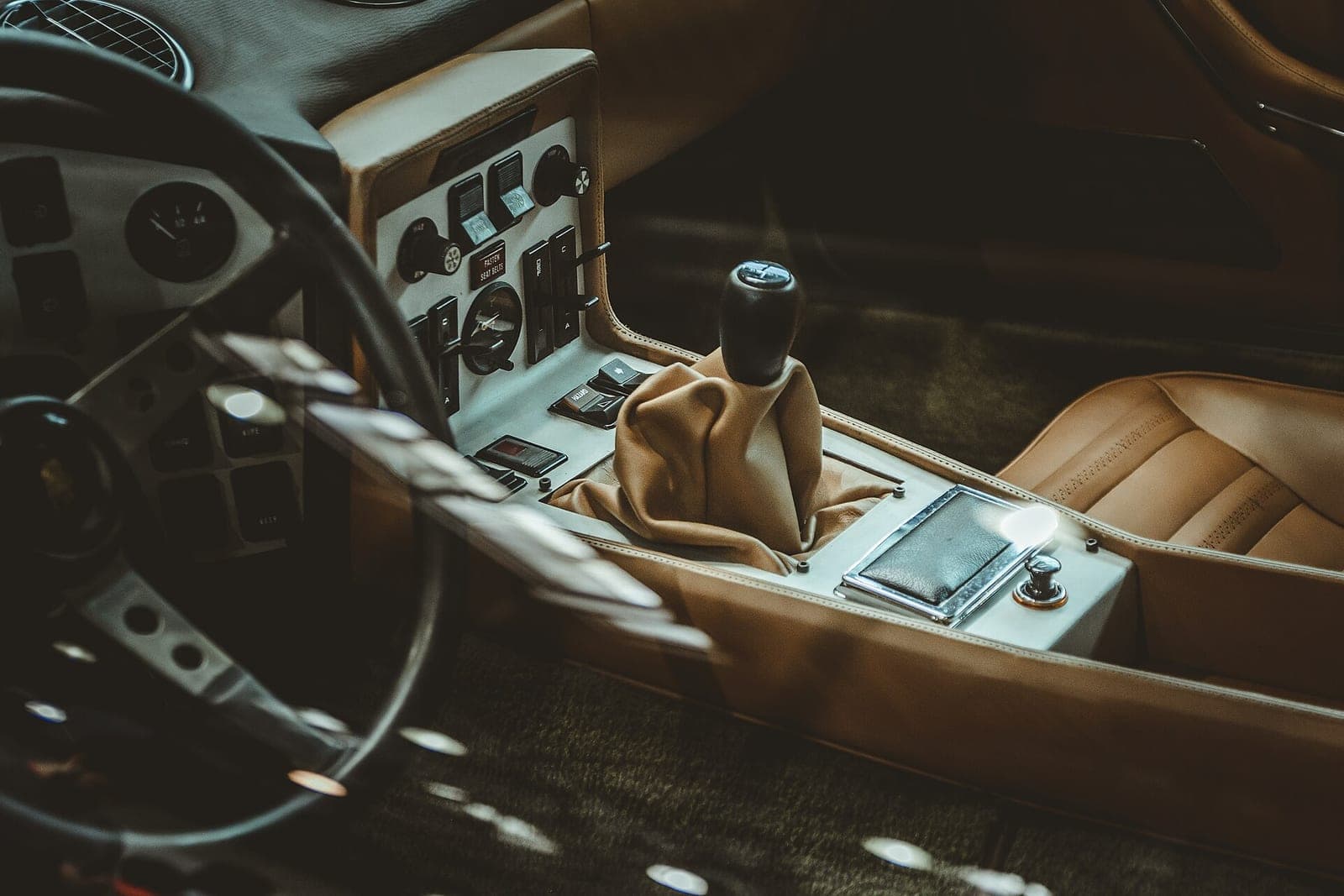 A car interior with tan leather seats, a leather shift boot and a center console of switches