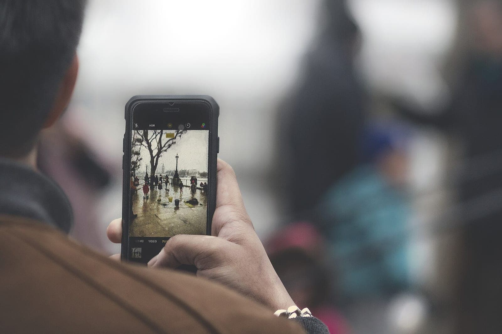 A person holds up a phone and frames a street scene on the screen