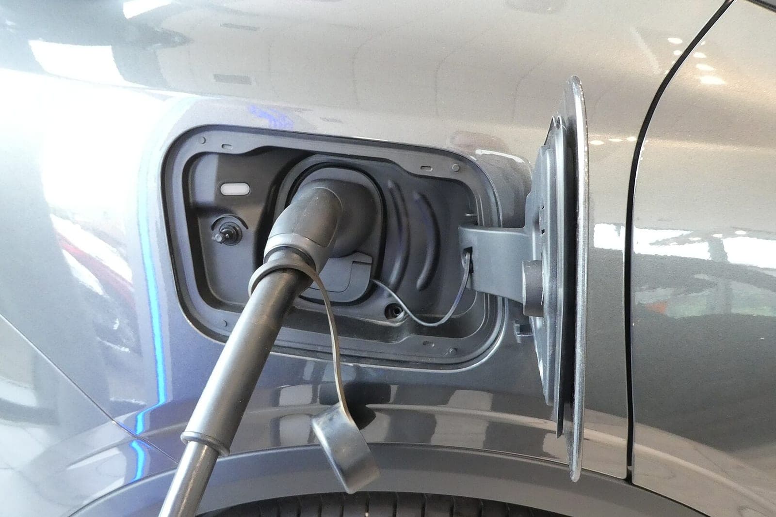 A charging cable plugged into the port of a gray SUV indoors