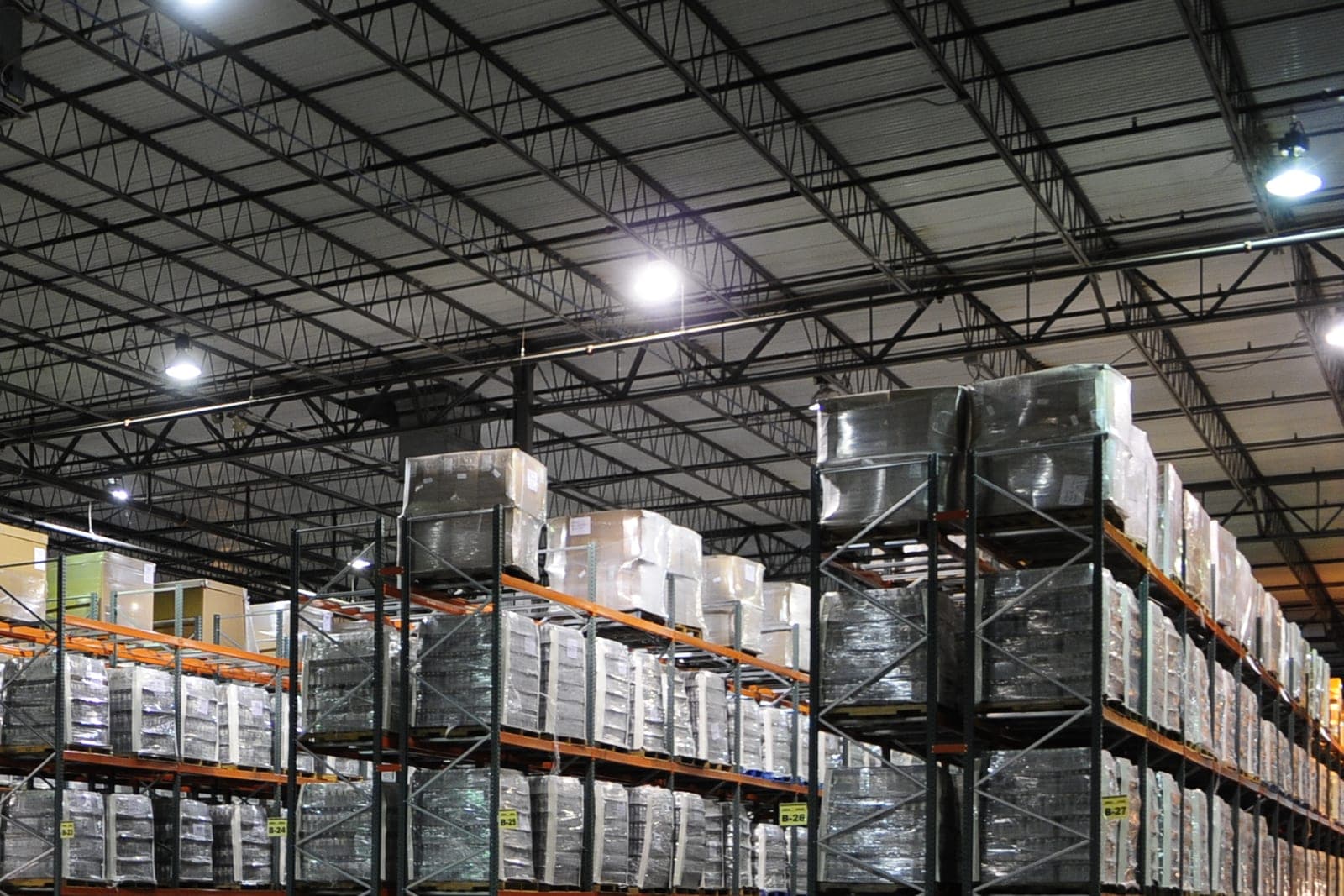 Tall warehouse racks holding shrink-wrapped pallets stacked with cases