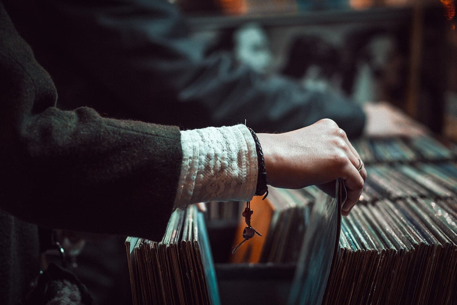 A shopper's hand flipping through a bin of records in a record shop
