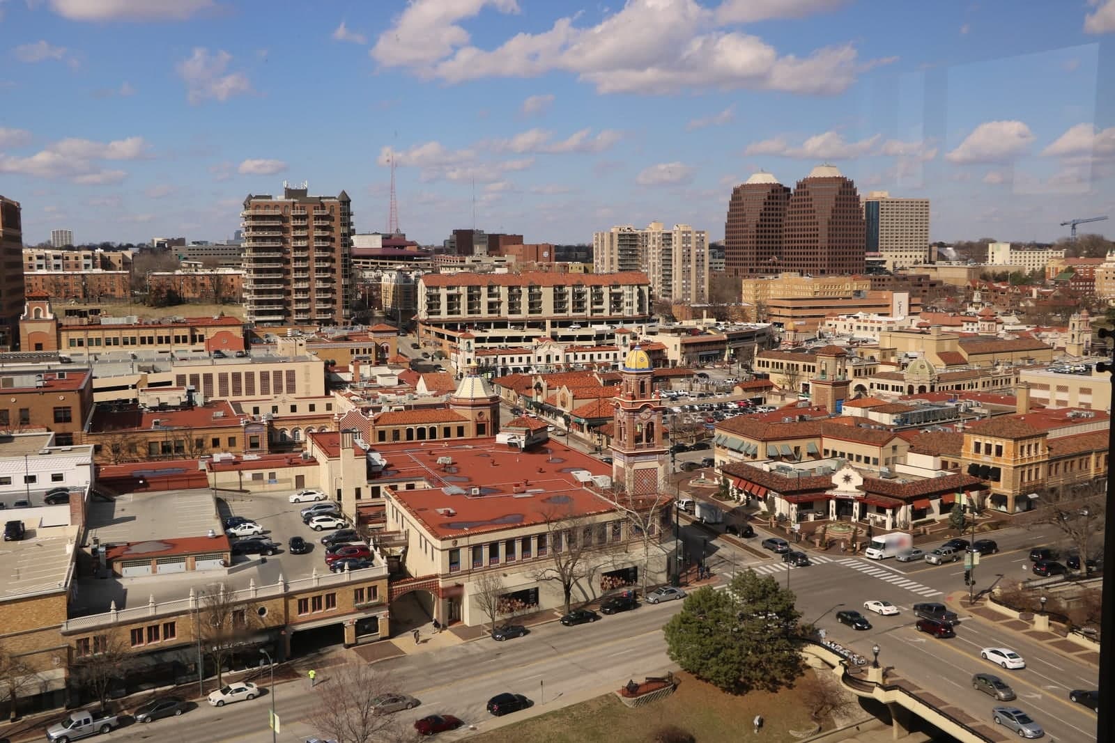 Red-tile roofs, Spanish-style towers and busy streets seen from above on a sunny day in Kansas City, Missouri