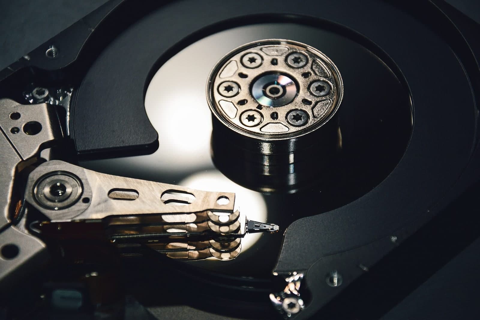 A close view inside an opened hard drive, showing the shiny platter, the spindle and the read arm