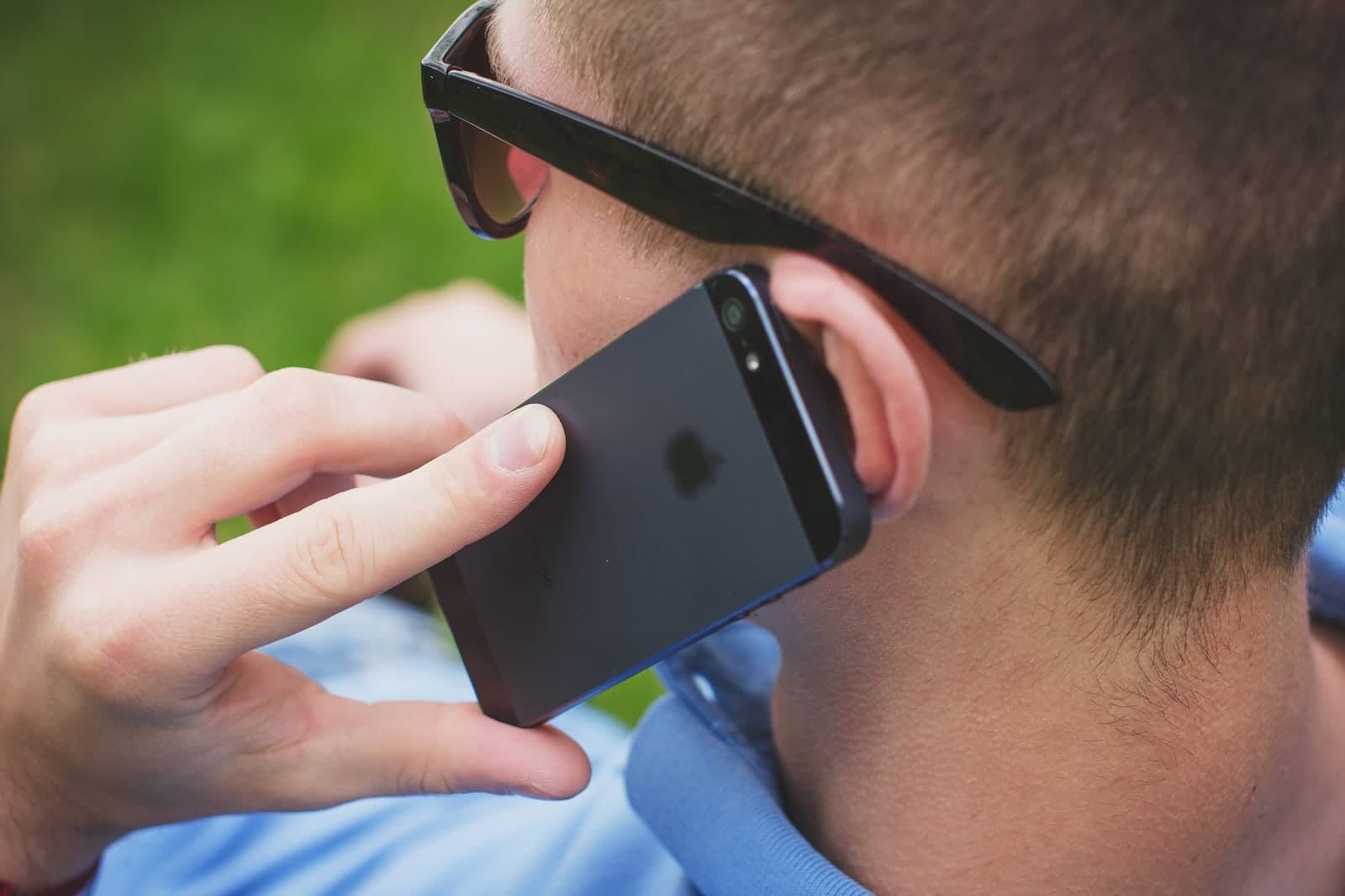 A man seen from behind holds a smartphone to his ear during a call