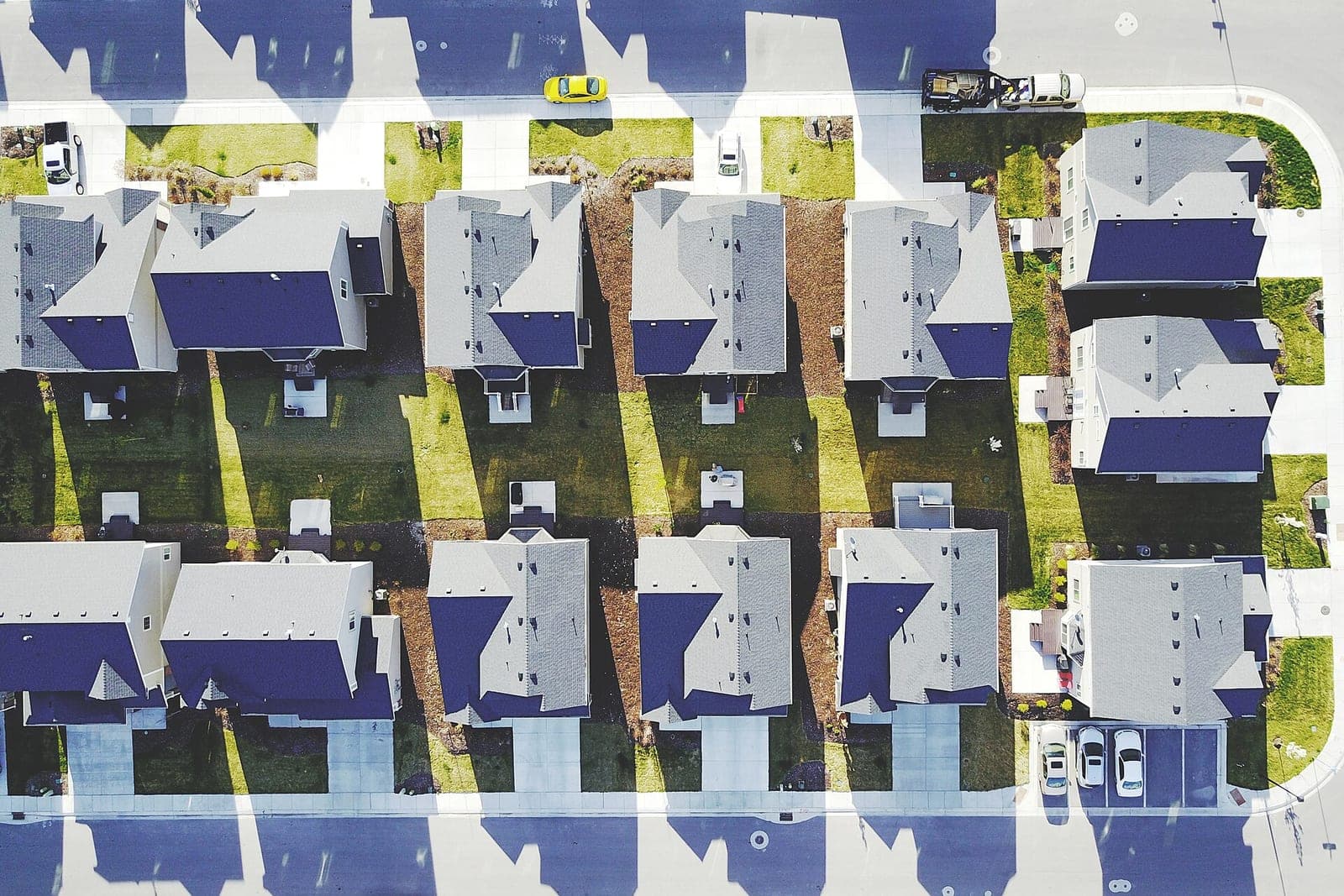 An aerial view of a new neighborhood with rows of houses, driveways and sidewalks