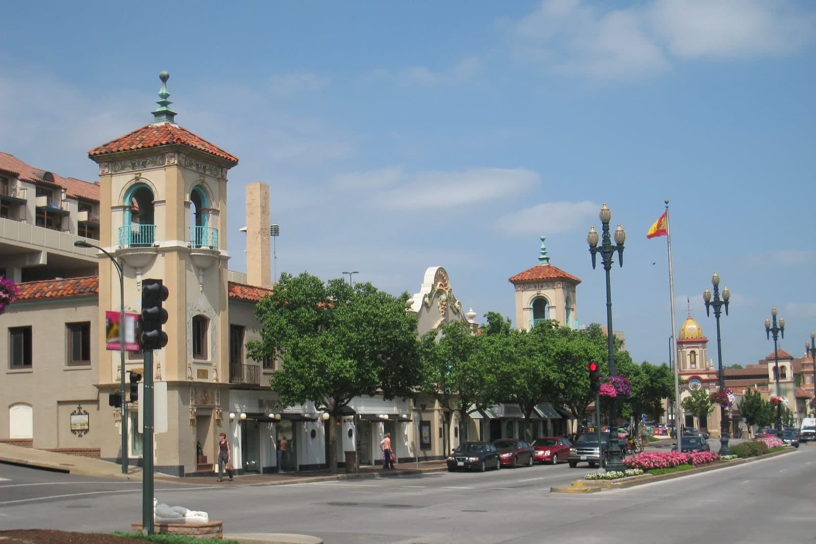 A street in the Country Club Plaza in Kansas City, Missouri, with Spanish-style towers, trees and flower beds under a blue sky