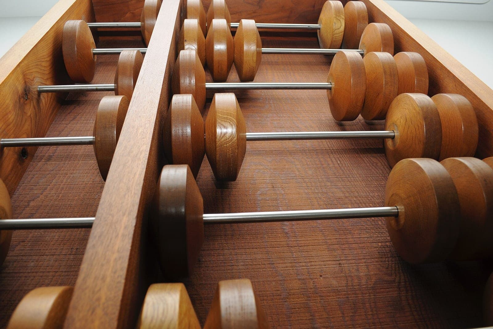 Large wooden beads sit on steel rods inside a big wooden abacus
