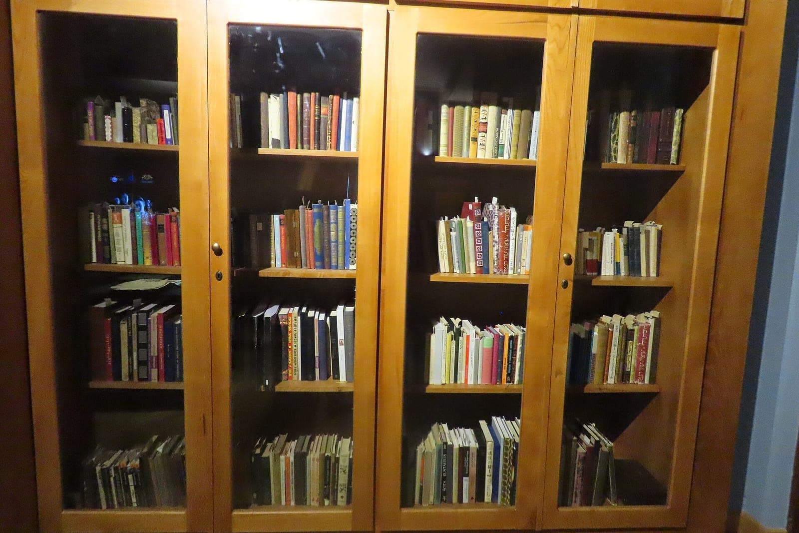 A wooden bookcase with glass doors filled with rows of books