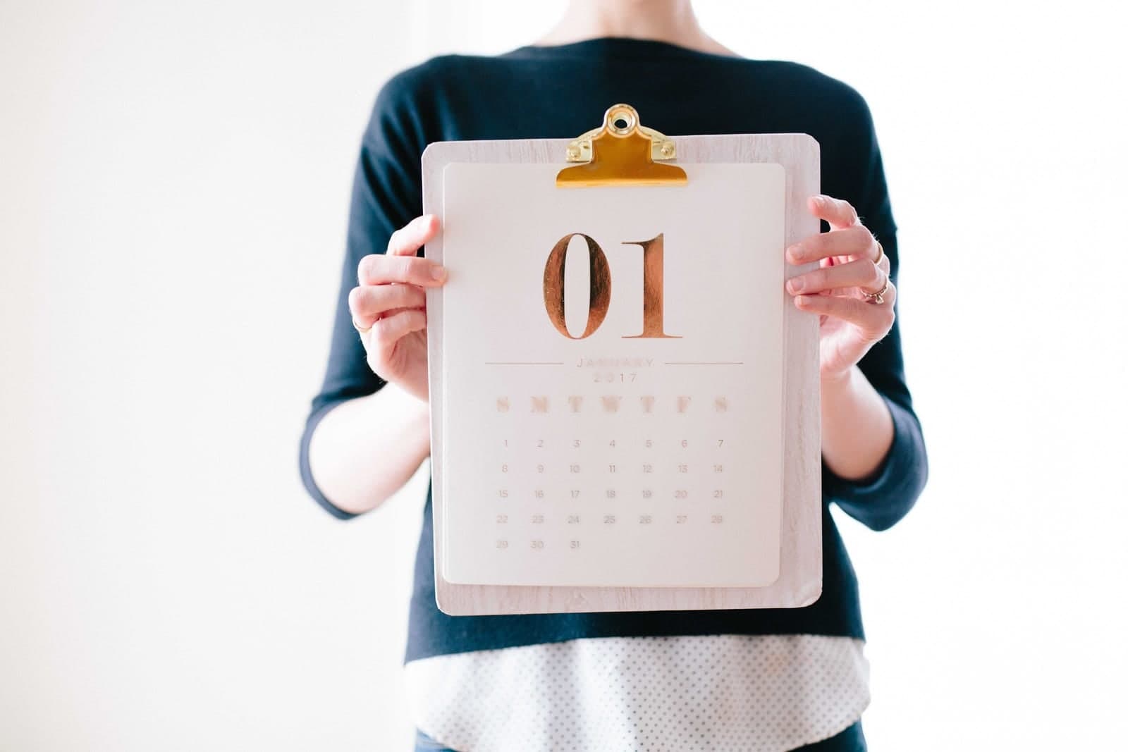 A person holds up a monthly calendar clipped to a clipboard