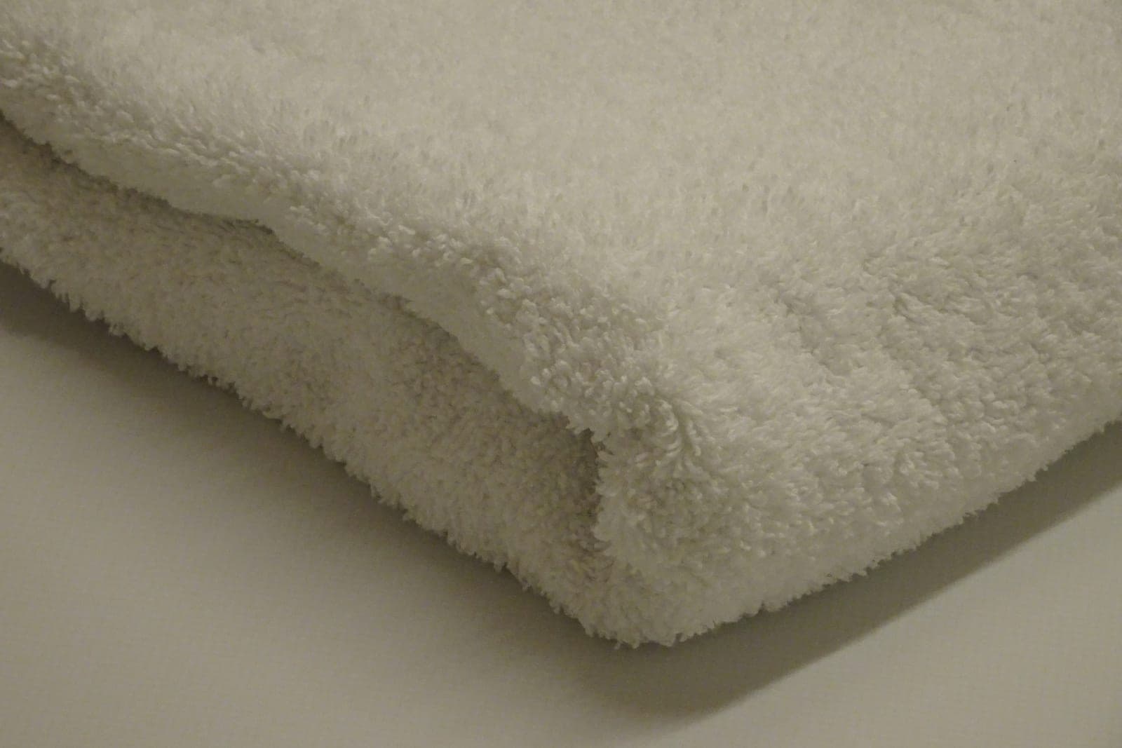 A thick white towel folded on a pale surface