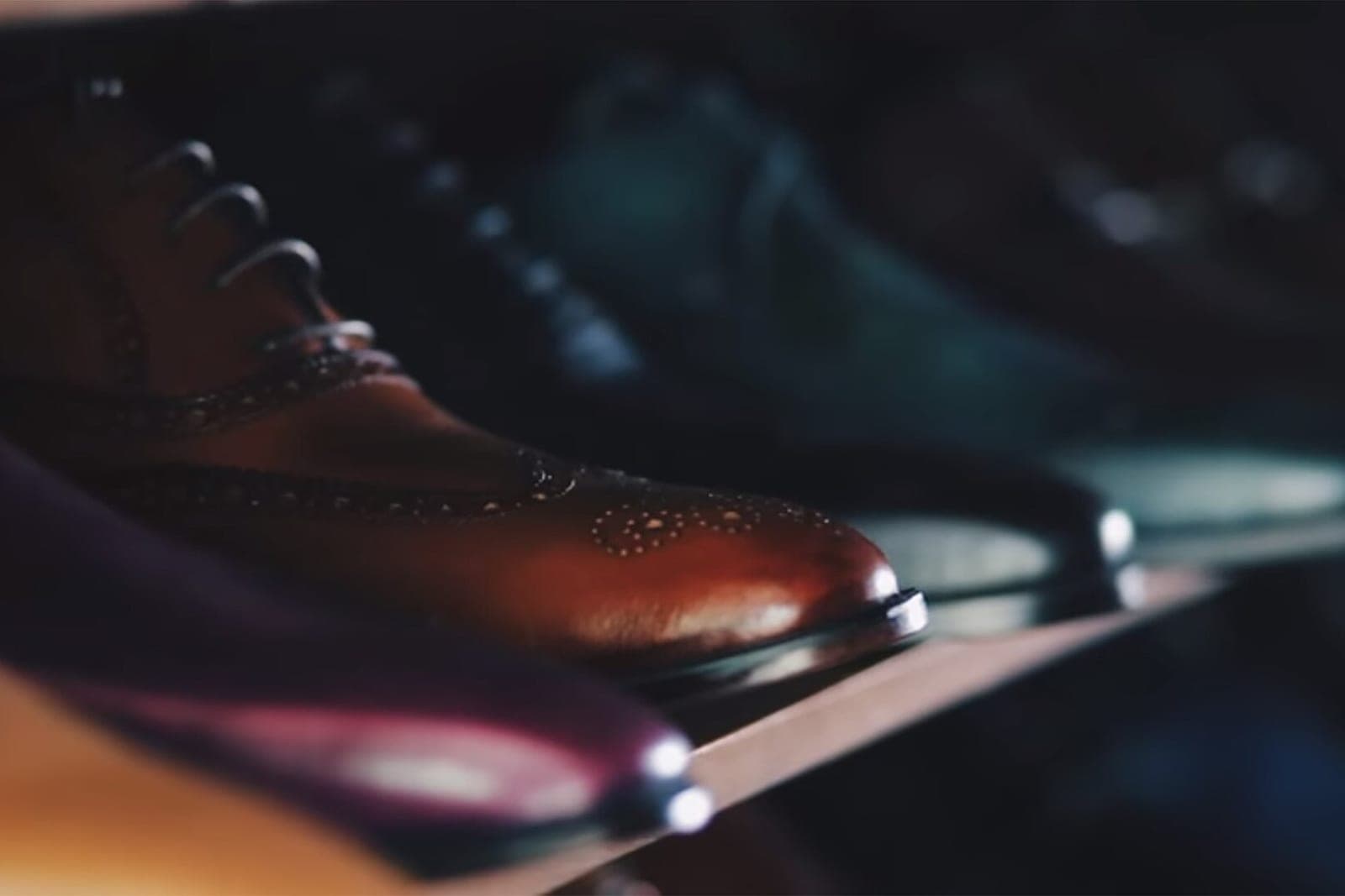 Polished leather dress shoes lined up on a wooden shelf in a small shop