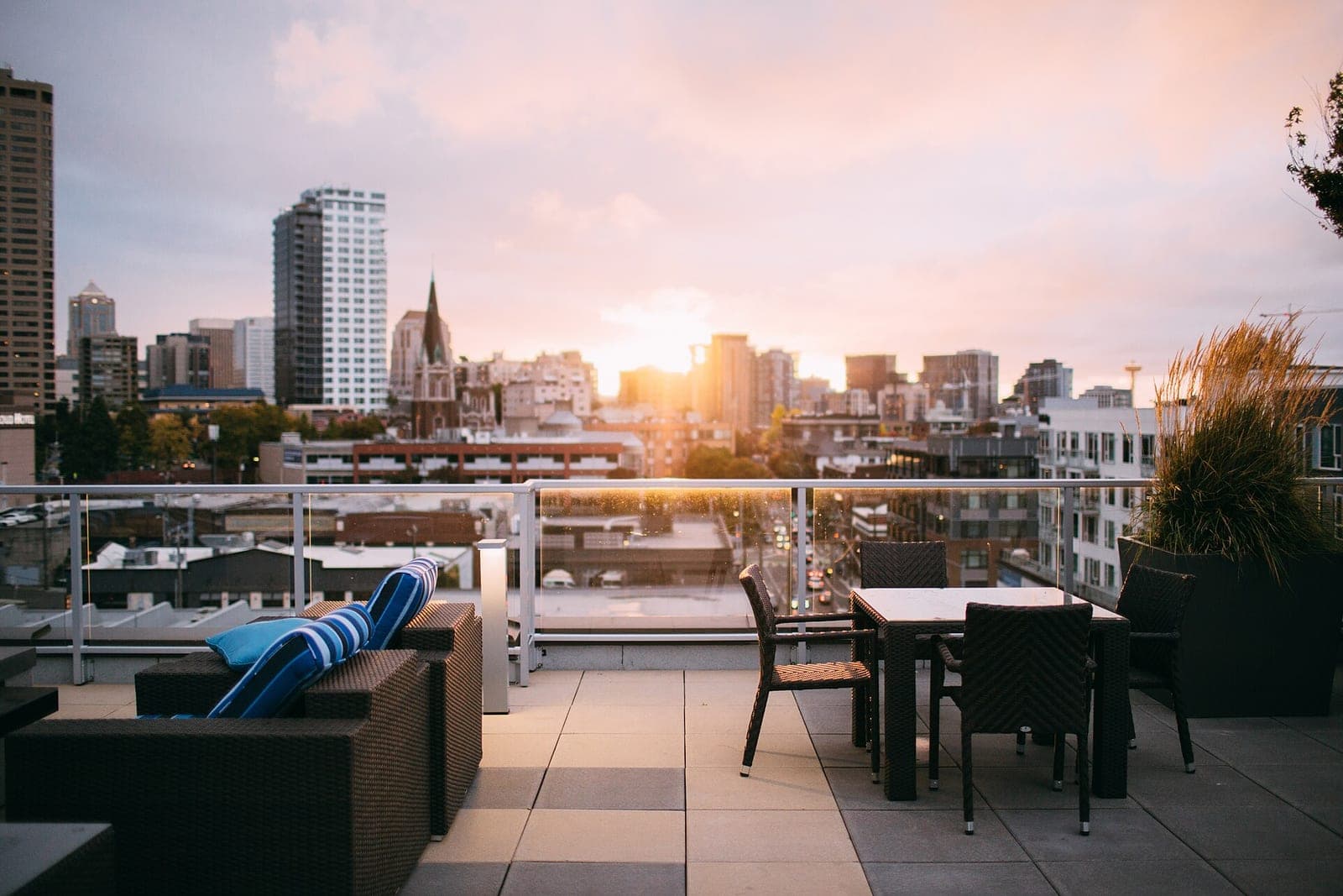 A rooftop terrace on an apartment building with chairs and a table at sunset over the city