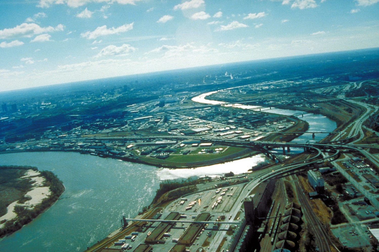 An aerial view of the Kansas River joining the Missouri River at Kansas City, with rail yards and highways along the banks