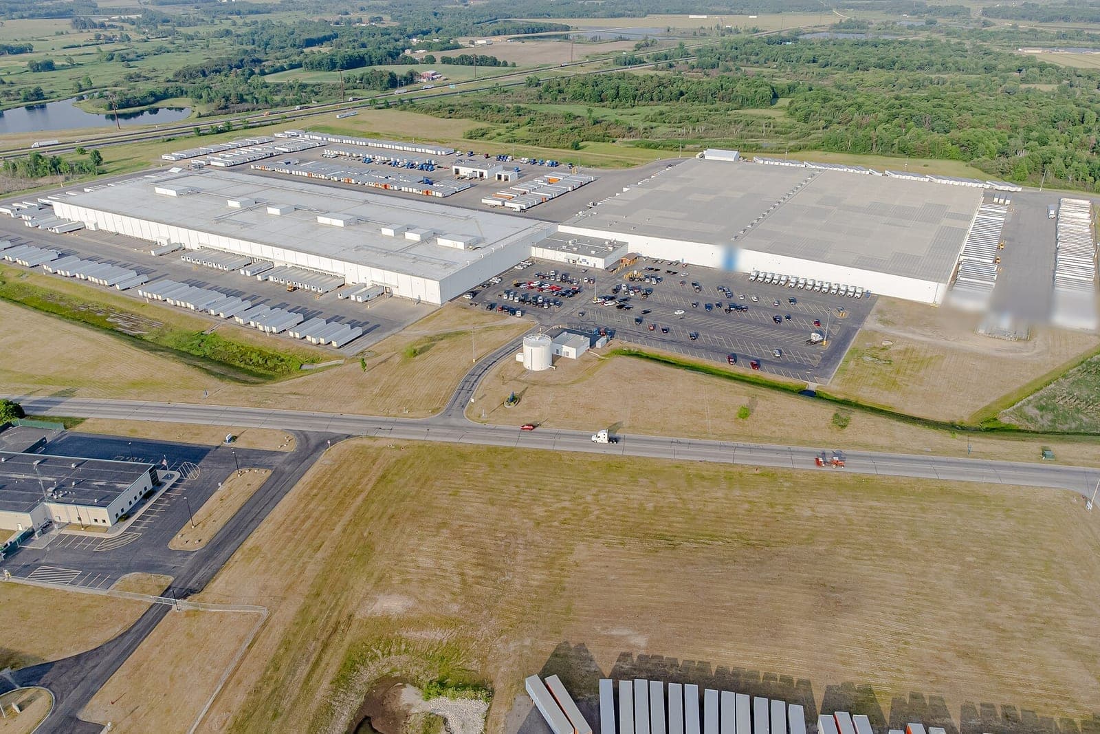 An aerial view of a large distribution center with rows of trailers backed up to its loading doors